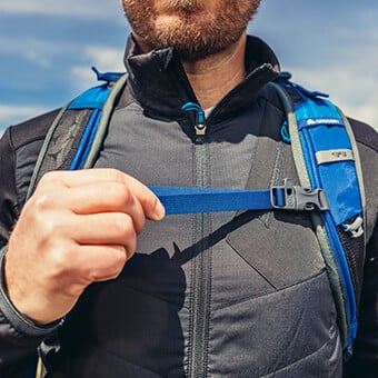 Perforated shoulder harness with sternum strap featuring integrated safety whistle